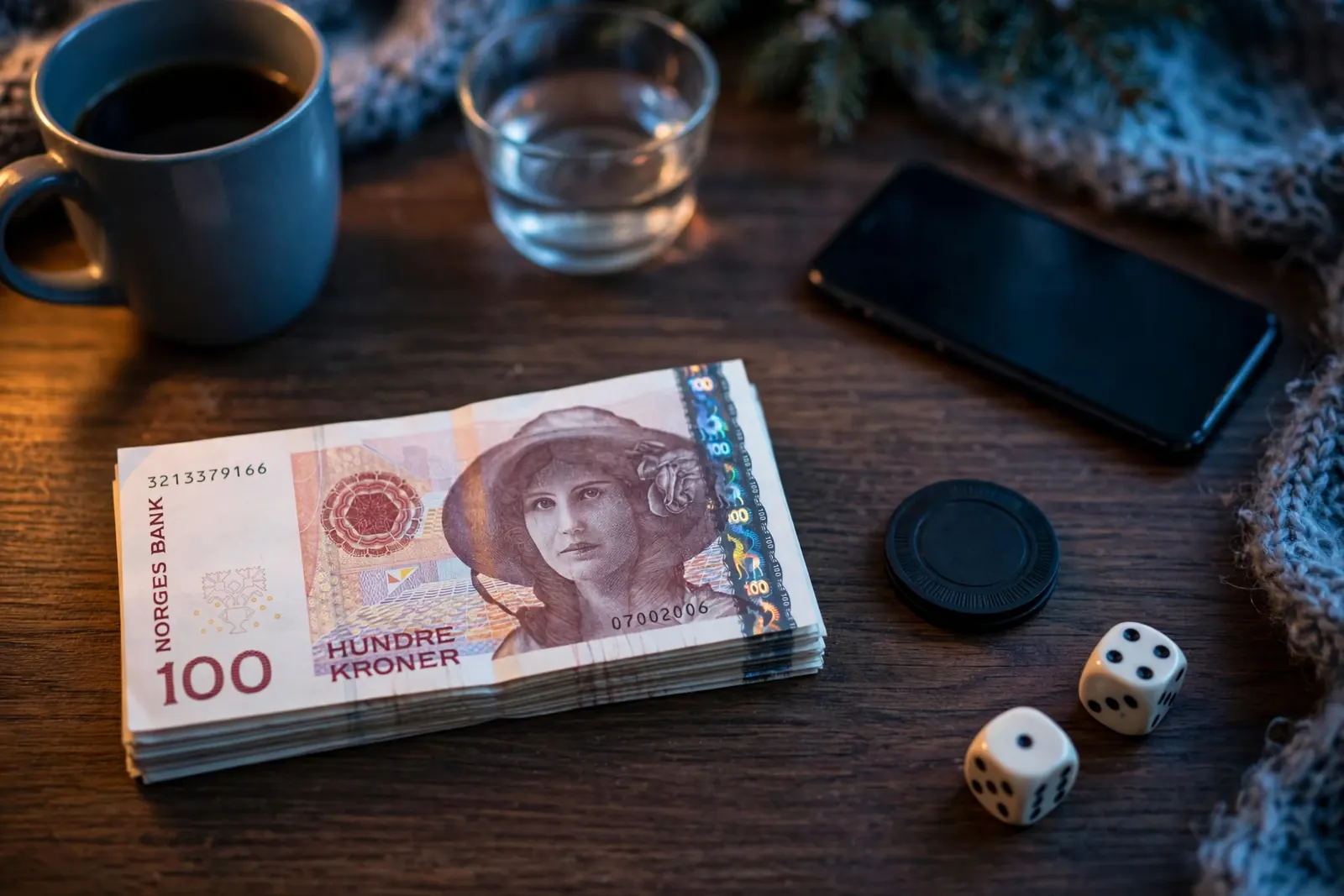 Norske 100-kroner sedler og en casinobrikke på et mørkt trebord